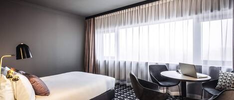 Una habitación de hotel con una cama, un escritorio, una computadora portátil y una silla.