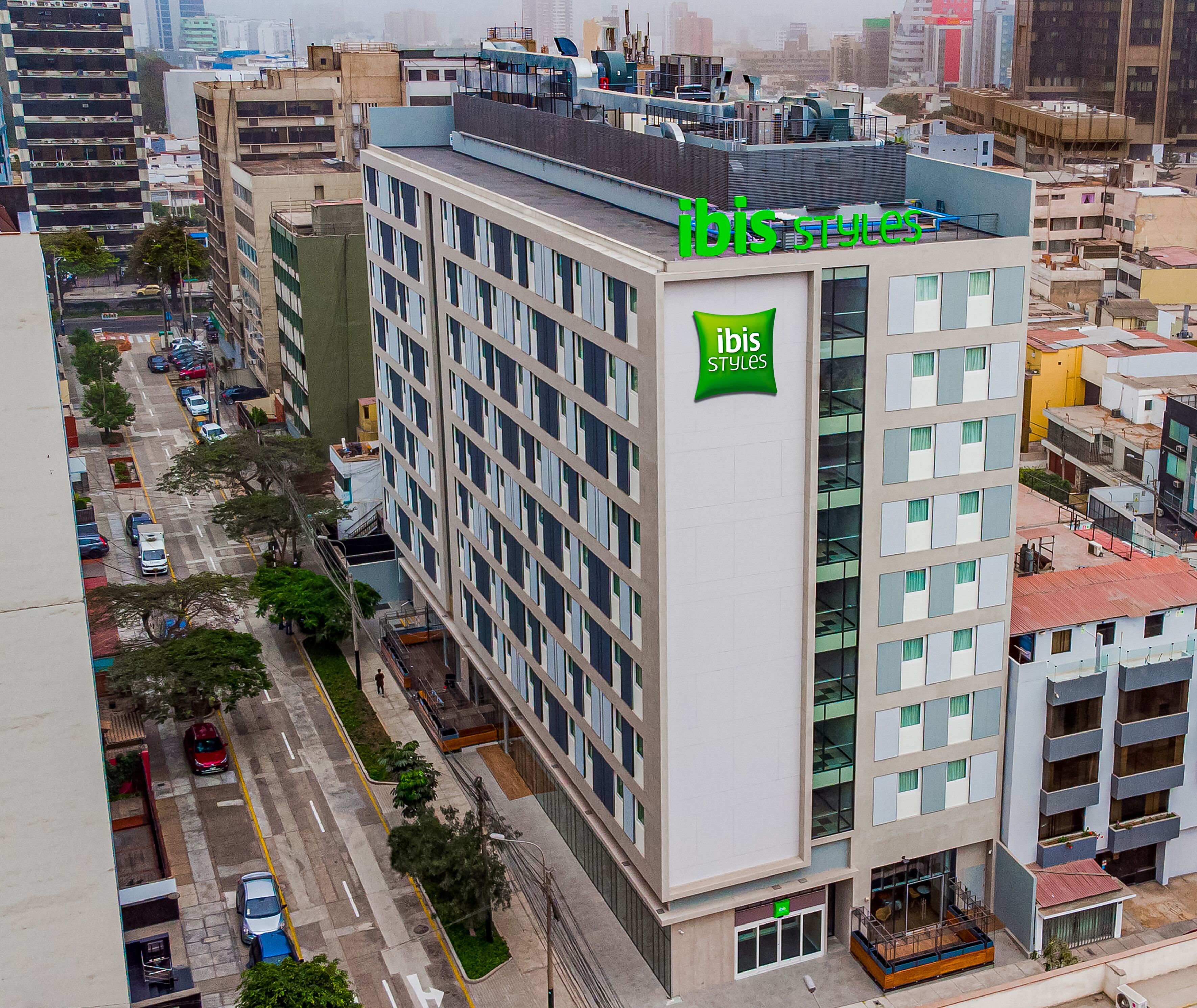 A multi-story building with a prominent green sign reading "ibis styles" on the facade.