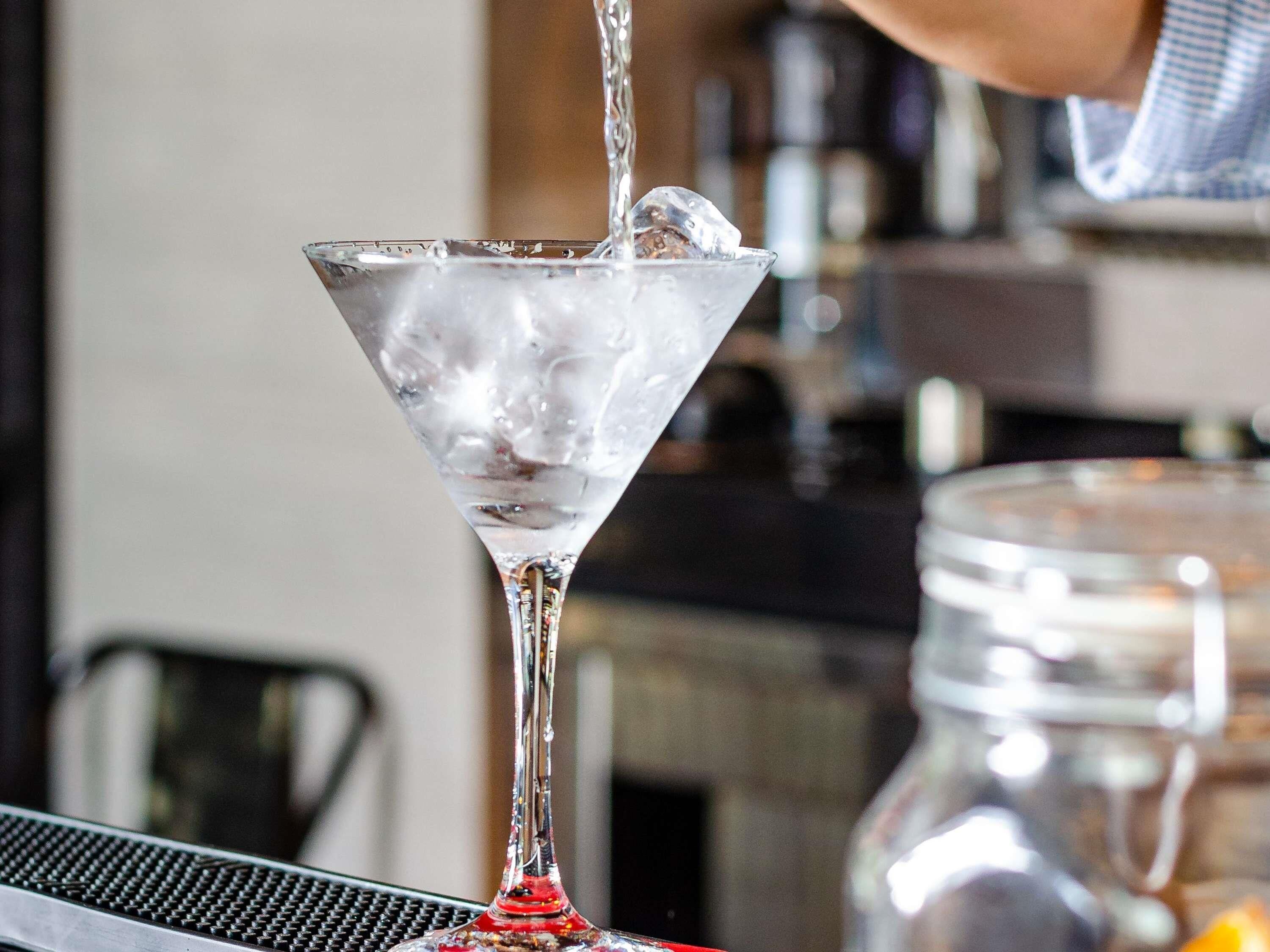 Una copa de martini con cubitos de hielo sobre una barra.
