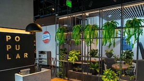 Un espace d’accueil avec un comptoir en marbre, une enseigne indiquant «Ouvert au public» et des plantes d’intérieur.