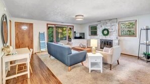 Ein geräumiges Wohnzimmer mit Kamin, einer Couch, einem Couchtisch und einem Fernseher.