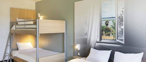 Habitación con literas, una mesita de noche con lámpara y ventana con vistas al exterior.