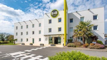 Experience the welcoming atmosphere of this B&B Hotel, surrounded by lush landscaping and a vibrant facade.