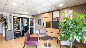 A lobby with seating, vending machines, and a large plant. - B&B HOTEL Vannes Ouest Golfe du Morbihan (Vannes)