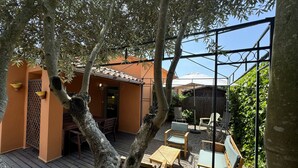 An outdoor patio with wooden furniture, a pergola, and a view of a building with a tiled roof. - Gregal 81 - A/C, pool and garden (Torroella de Montgri)
