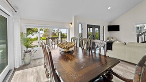 Un salón espacioso con una mesa de comedor de madera, asientos cómodos y ventanas amplias con vistas al exterior.