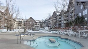 A swimming pool with a tiled deck, surrounded by buildings with a modern architectural style.