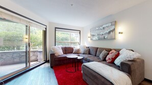 A modern living room with a sectional sofa, a small round table, and a red rug.