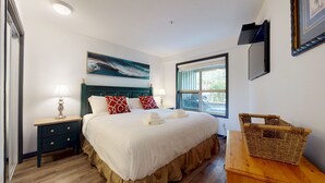 A neatly arranged bedroom with a bed, bedside tables, a window, and a painting on the wall.