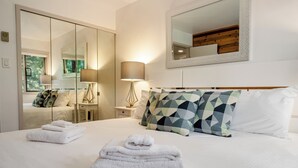 Une chambre d’hôtel avec un grand lit, une armoire, une table de chevet avec une lampe et un miroir au mur.