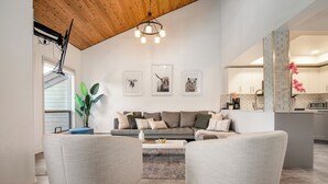 Un salon moderne avec un canapé gris, deux fauteuils, une table basse et des tableaux représentant des animaux, accrochés au mur.