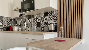 Una cocina moderna con una mesa de madera, sillas blancas y un salpicadero con diseño.