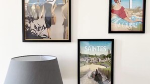 Tres obras de arte enmarcadas en una pared, una lámpara moderna y una escalera.