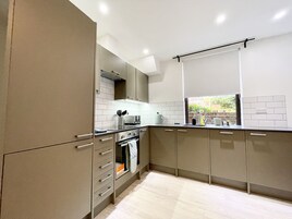 Una cocina moderna con horno integrado, microondas y hervidor en la encimera.