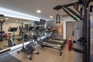 Un gimnasio con cintas de correr, elípticas y una banca para pesas.
