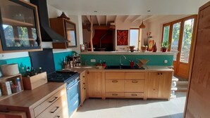 Una cocina moderna con armarios de madera, una isla central y un ventanal con vistas a un jardín.