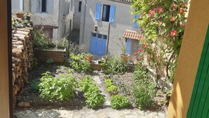 Un patio con muro de piedra, plantas en macetas y una puerta azul.