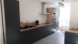 Een moderne keuken met donkere kastjes, een houten aanrecht en een ingebouwde oven.