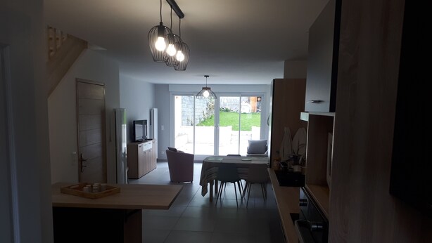 Een moderne keuken met een eethoek, een televisie en een schuifdeur naar een terras.