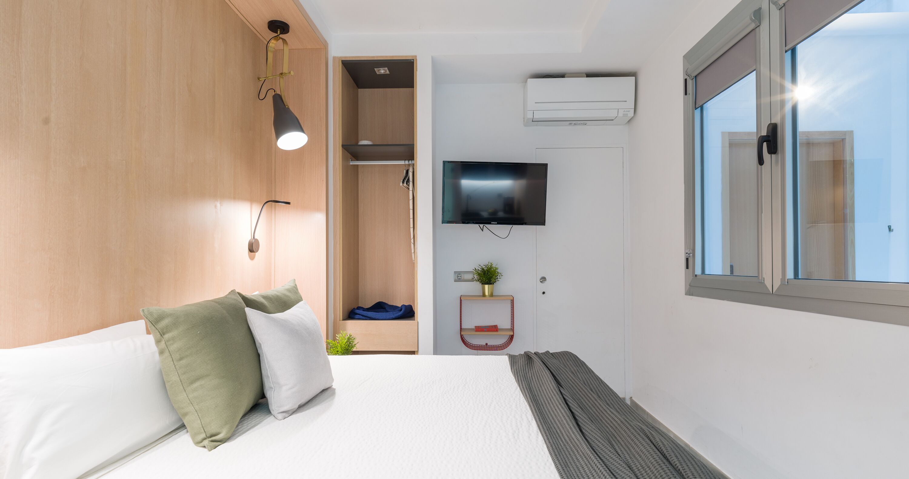 Una habitación de hotel moderna con cama, televisión, aire acondicionado y ventana.