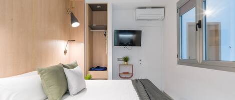 Una habitación de hotel moderna con cama, televisión, aire acondicionado y ventana.