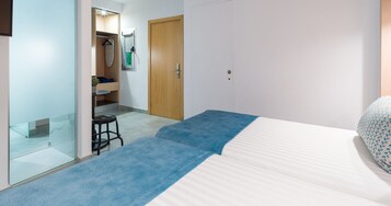 A bedroom with a bed, a small stool, a mirror, and a wardrobe.