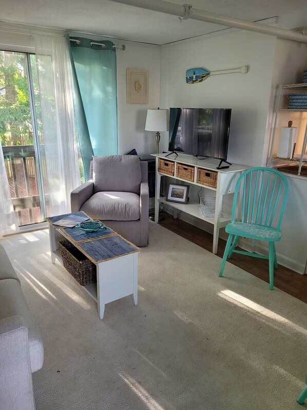 A living room with a grey sofa, a teal chair, a TV, and a lamp.