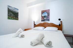 A neatly made bed with white linens and towels, a wooden headboard, and two wall-mounted lamps. - Bahia 46 Apartments by Casasol (Nerja)