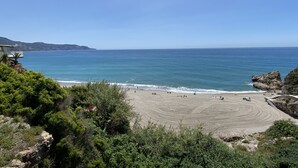 Une plage offrant une vue dégagée sur l’océan et les collines lointaines.