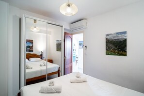 A hotel room with a bed, a wardrobe, a door leading to another room, and a painting on the wall.