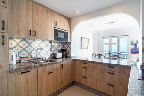 A modern kitchen with wooden cabinets, a built-in microwave, and a granite countertop.