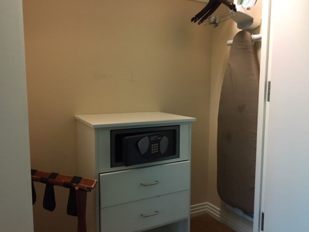 Una habitación compacta con un microondas sobre un mueble pequeño, un perchero y un espejo grande.