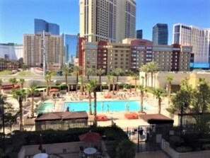 A hotel with a pool area, surrounded by palm trees and modern buildings in the background. - No Resort Fee MGM Signature Condo with Balcony - Great View! In-room Jacuzzi! (Las Vegas)