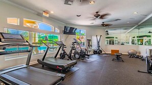 Une salle de sport équipée de tapis de course, de vélos d’appartement et d’autres appareils d’exercice.