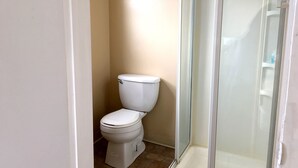A bathroom with a toilet, a shower enclosure, and a white door. - Half Block from Belmar Beach!! (Belmar)