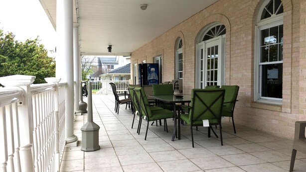 A covered outdoor patio with a brick wall, white railings, and green chairs. - Half Block from Belmar Beach!! (Belmar)