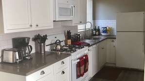 Eine moderne Küche mit weißen Schränken, einer Mikrowelle, einem Herd und einem Kühlschrank.