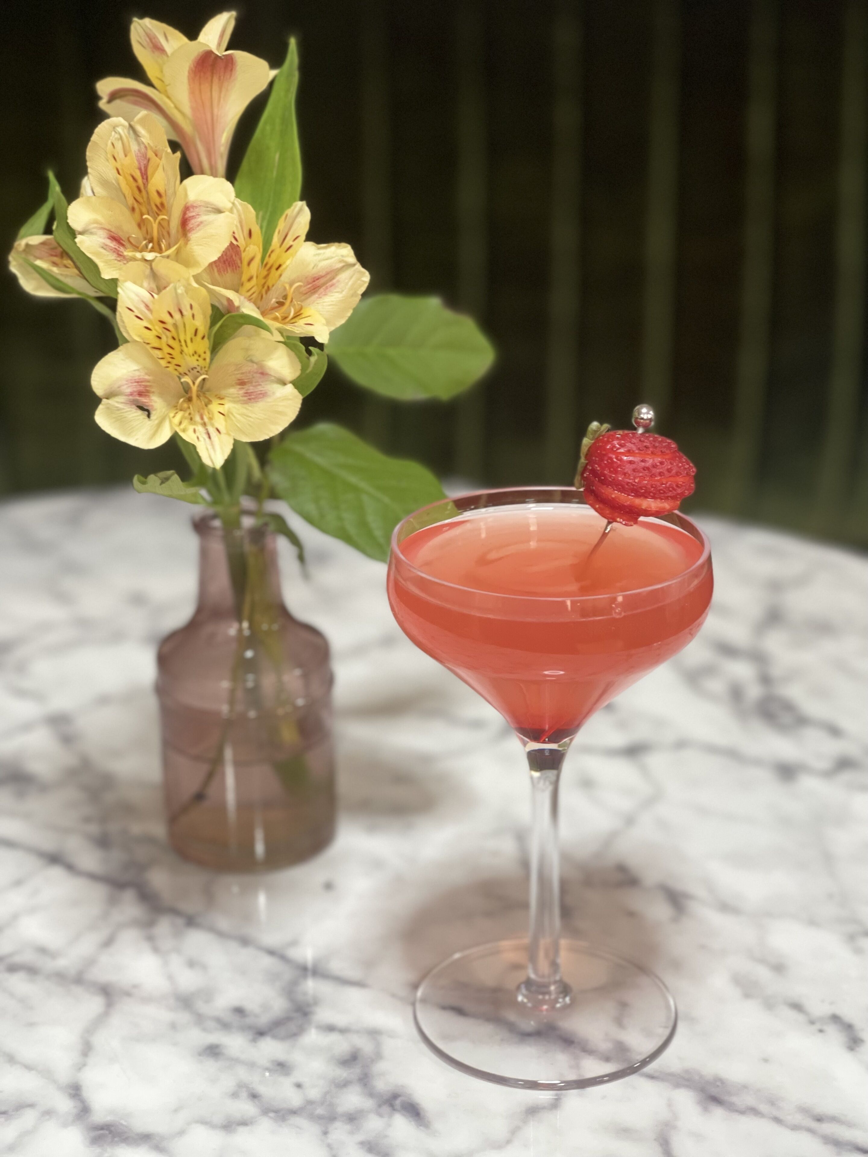 Ein Martini-Glas mit Erdbeere auf einer Marmorplatte.