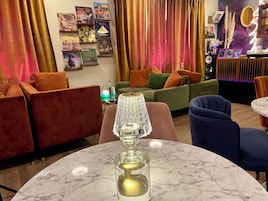 Una sala de estar moderna con una mesa de mármol, sofás rojo y verde, y una lámpara decorativa.