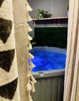 Un hidromasaje con interior azul, rodeado por una cortina color beige con flecos.