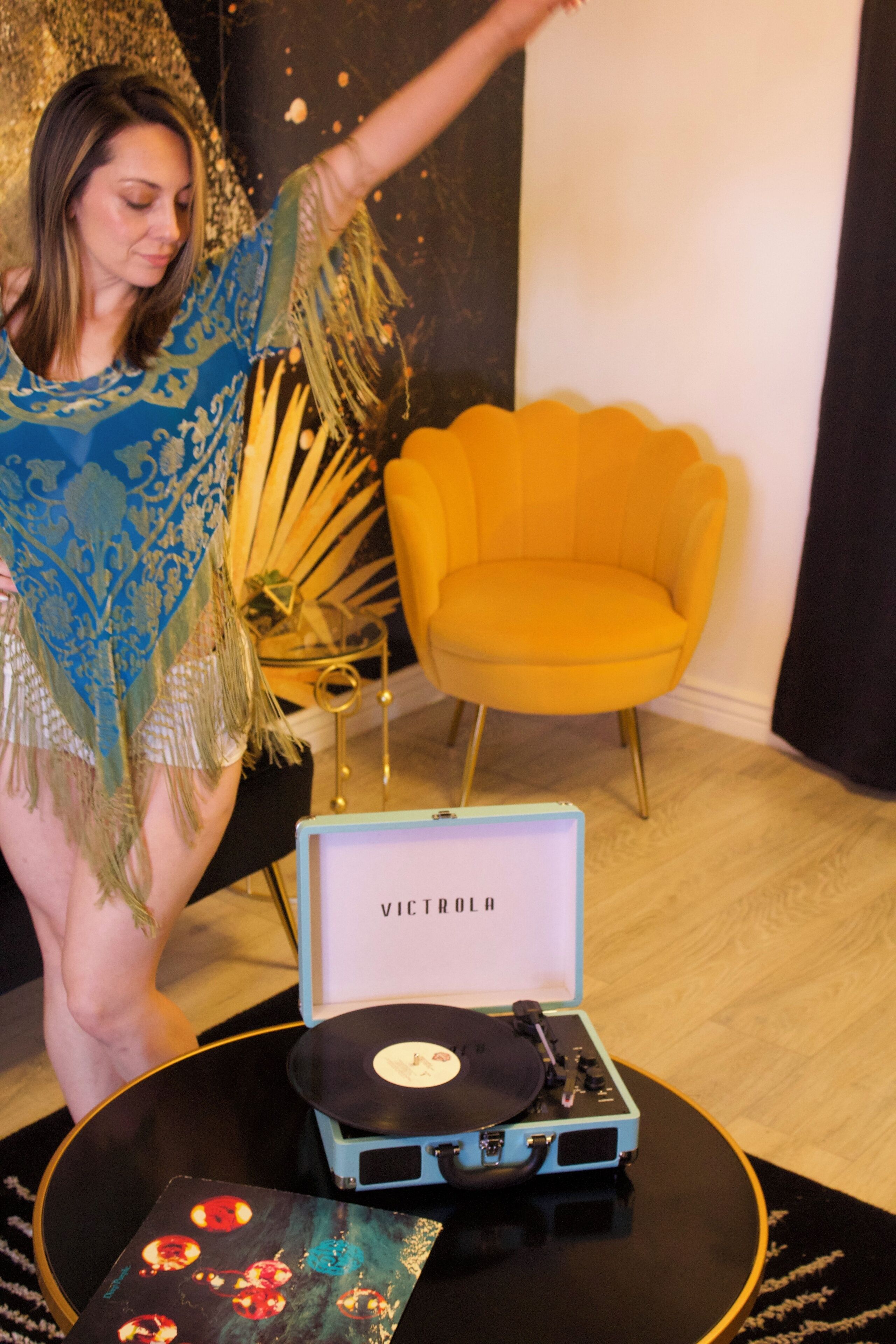A room with a vintage turntable and vinyl records on a black table.