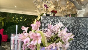 A table with a vase of pink flowers, a water bottle, and a book titled "The Secret Language of Color". - Hotel Zazz (Albuquerque)