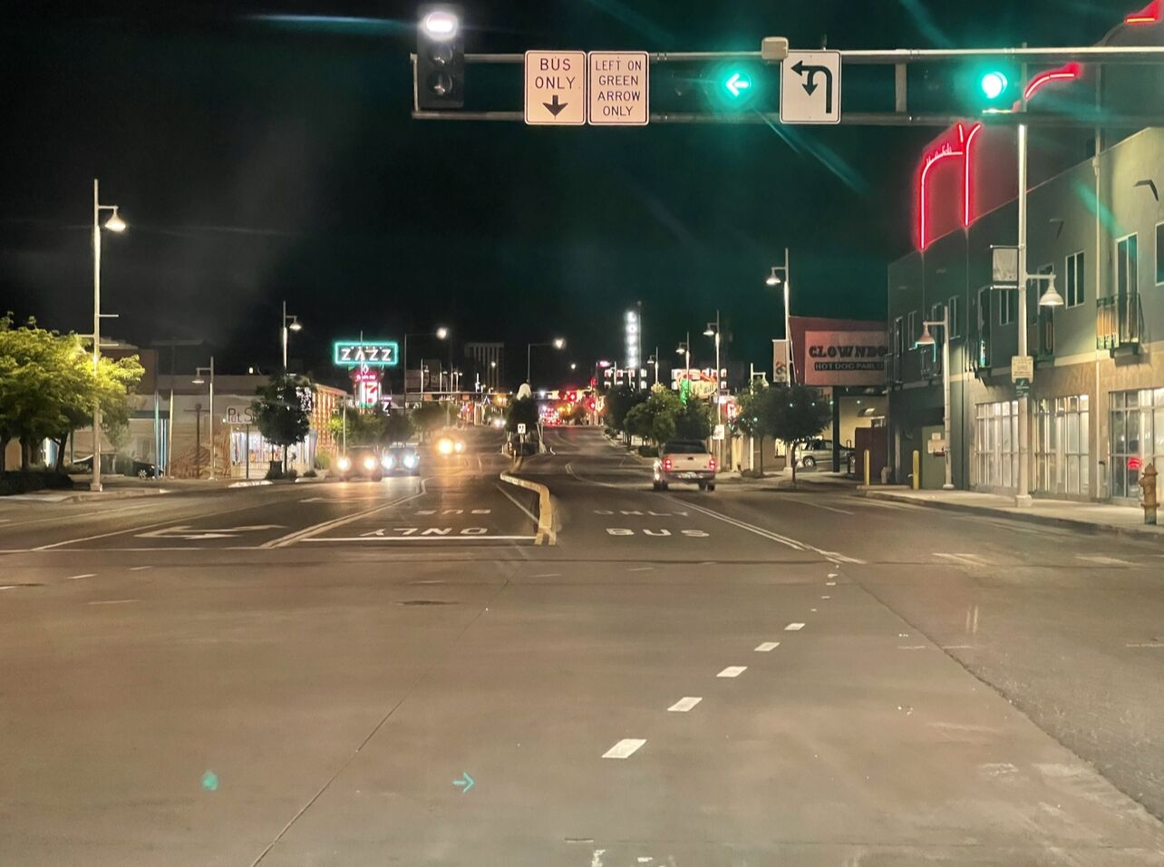 Une intersection de rue illuminée la nuit, avec des feux de signalisation et des panneaux de direction.