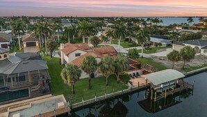 A residential area with houses, palm trees, and a dock extending into a body of water. - WALK TO BEACH • Waterfront •Direct Gulf Access •South Facing Heated Pool • 4  Kings (Cape Coral)