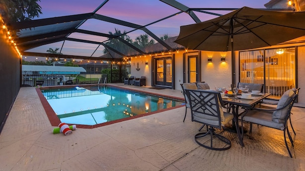 A covered outdoor area with a swimming pool, patio furniture, and string lights. - WALK TO BEACH • Waterfront •Direct Gulf Access •South Facing Heated Pool • 4  Kings (Cape Coral)