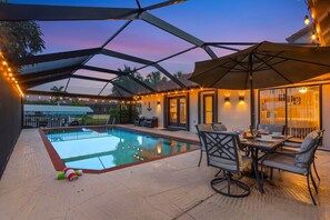 Ein überdachter Außenbereich mit Pool, Terrassenmöbeln und Lichterketten.