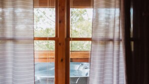 Une fenêtre donnant sur du mobilier de jardin et des arbres.
