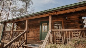 Une cabane rustique en bois, avec une porte verte, une véranda en bois dotée d’une balustrade et le numéro « 540 » affiché sur la porte.