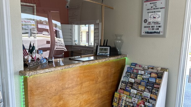 Un espace d’accueil comprenant un comptoir en bois, une horloge numérique et un panneau d’affichage contenant des informations pour les visiteurs.