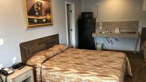 Une chambre d’hôtel équipée d’un lit, d’un bureau avec un téléphone, d’un réfrigérateur, d’un four à micro-ondes et d’une petite kitchenette.